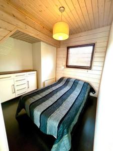 1 dormitorio con 1 cama en una habitación de madera en Aurinkopaikka 4 Himos, en Jämsä