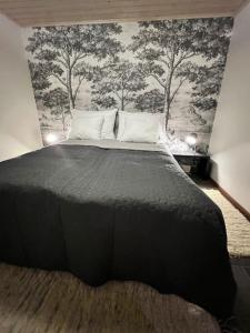 a bedroom with a black bed with trees on the wall at Kuikanhovi B Himos in Jämsä