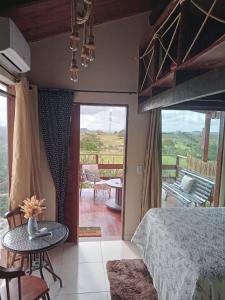 a bedroom with a bed and a table and a balcony at Chalé Adventure in Nova Cruz