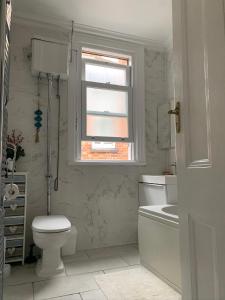 a white bathroom with a toilet and a window at 38 Whitehall Road in Harrow on the Hill