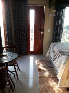 a bedroom with a bed and a table and a door at Chalé Adventure in Nova Cruz