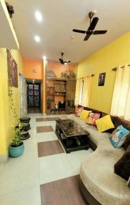 uma sala de estar com um sofá e uma ventoinha de tecto em Feel the Bong vibes in a villa nearest to airport. em Calcutá