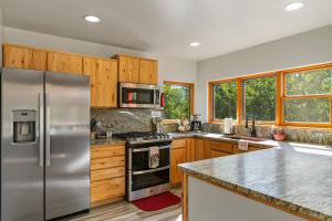 a kitchen with a stainless steel refrigerator and wooden cabinets at Secluded Mtn home by Purg, Hot Tub, Views! Pets ok in Durango