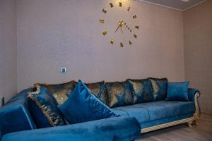 a blue couch in a living room with a clock on the wall at Luxury Milan Gabala hot pool, mountain view, cable car in Gabala