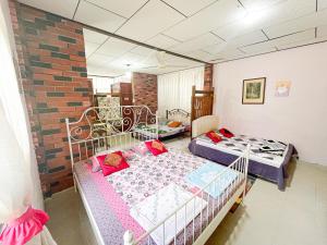 a bedroom with two beds and a brick wall at Dusun Indah Cottage 2 in Bayan Lepas
