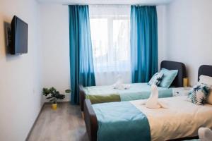 two beds in a room with blue curtains at Casa LUCAS in Bistriţa