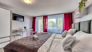 a bedroom with a bed and a window with red curtains at Maja Pokoje z Widokiem & SPA - Kameralne Noclegi Agrotustystyczne na Pogórzu Izerskim in Mirsk