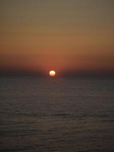un coucher de soleil sur l'océan et le soleil à l'horizon dans l'établissement Suite ortigia vista mare, à Syracuse