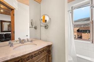 a bathroom with a sink and a mirror and a window at Independence Square Unit 306 in Aspen