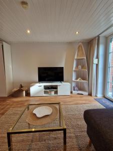 a living room with a tv and a table at Ferienwohnungen Dümmersee - Haus Alter Pferdestall in Hüde