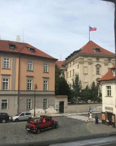 une voiture rouge garée dans un parking en face d'un bâtiment dans l'établissement Hradčany apartment with green energy, à Prague