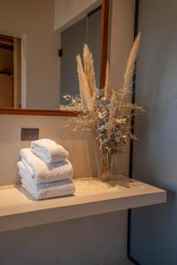 a bathroom counter with towels and a vase of dry grass at Las Terrazas Hotel Boutique in Tilcara