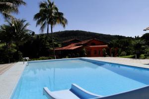 a large blue swimming pool in front of a house at Hotel dos Bretões in Sumidouro