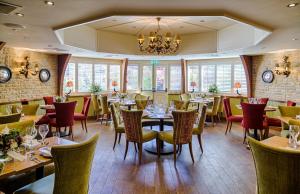 um restaurante com mesas e cadeiras e um lustre em The Crown Inn em Peterborough