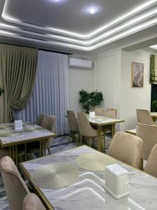 ein Esszimmer mit Tischen, Stühlen und Vorhängen in der Unterkunft KORKEM Palace Hotel and Spa in Schymkent
