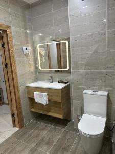 bagno con servizi igienici, lavandino e specchio di KORKEM Palace Hotel and Spa a Shymkent