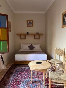 a bedroom with a bed and a table and chair at Riad Dar Les Freres in Marrakech