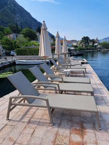 eine Reihe von Liegestühlen und Sonnenschirmen auf einem Dock in der Unterkunft Apartment Radimiri in Kotor