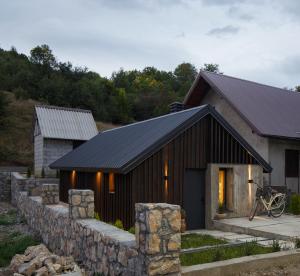 a small building with a stone wall next to a house at Wood cabin Kolasin in Kolašin