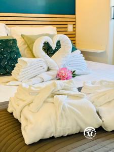 a bed with white towels and a flower on it at Gîte & Spa 4 étoiles - Le Villemachois - Neuf - Tout confort in Villemoustaussou