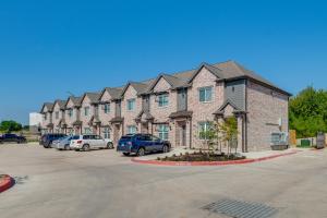 a large building with cars parked in a parking lot at Newly Built Corner Hideaway about 3 Mi to Texas AandM in College Station