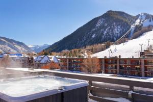 a hot tub on the roof of a hotel with a snow covered mountain at Independence Square 213, Spacious Hotel Room with 2 Queen Beds, Wet Bar, and Sitting Area in Aspen