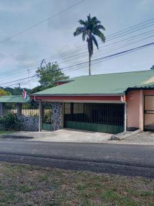 a building with a green roof and a palm tree at Apartamento Lopez y Azofeifa in Portete