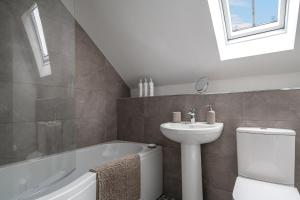a bathroom with a sink and a toilet and a bath tub at Spacious and modern family apartment, central and within walking distance to local amenities in Abergele