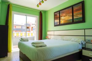 a bedroom with a bed with green walls and a window at South Coast Apartment in Puertito de Güímar