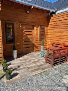 Cabaña de madera con 2 bancos frente a ella en Hostal Entre Los Lagos en Villarrica
