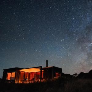 a cabin in the middle of a field at night at Whitimanuka Retreat in Martinborough 
