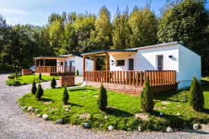 a small white house with a yard with trees at Beaumont Lodges in Predeluţ