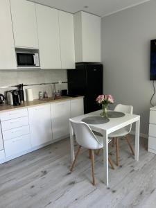 a kitchen with a white table and chairs and a table with flowers at Apartament na Dworcowej Centrum in Wrocław