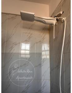 a shower with a hair dryer on a wall at WhiteRose Apartments in Meru