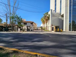 an empty street in front of a building with palm trees at Complejo Cerrado Zona Shopping in Guaymallen