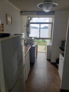 Dichato full vista al mar في تومي: مطبخ مع نافذة كبيرة وأرضية مطبخ