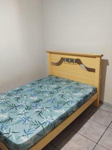 uma cama com uma moldura de madeira com um lençol azul em Glenda temporada em Olímpia