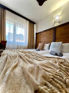 a bedroom with a large bed with a large blanket at Red House Family Hotel in Bansko