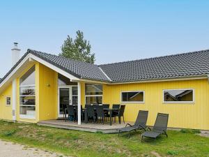 a yellow house with a table and chairs in front of it at Four-Bedroom Holiday home in Großenbrode 1 in Großenbrode