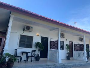 a white house with a table and chairs at Rerama Room Stay Langkawi in Pantai Cenang