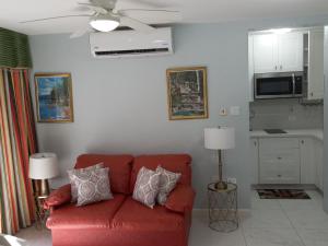a living room with a red couch and a kitchen at Marchabell by the Sea E22 in Ocho Rios