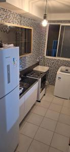 Il comprend une cuisine équipée d'une cuisinière et d'un réfrigérateur blanc. dans l'établissement Pedacinho de Lar, à João Pessoa