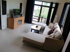 a living room with a couch and a television at Viking House Villa Deluxe in Koh Tao