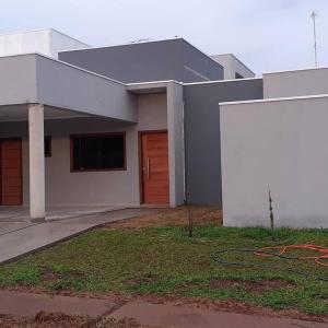 - un grand bâtiment blanc avec une porte rouge dans l'établissement Pirassununga, SP - Casa 3 suítes em condomínio RURAL - 06 hóspedes Confortáveis, à Pirassununga
