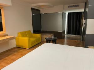 um quarto com uma cadeira amarela e uma mesa em NewPort Love Hotel em Cidade do México