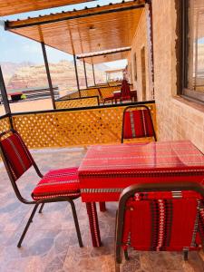 una mesa roja y 2 sillas en un patio en wadi rum bedouin stars camp, en Wadi Rum 20 fotos más