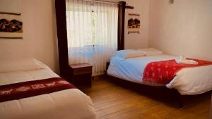 1 dormitorio con 2 camas y ventana en Mirador inka, en Ollantaytambo