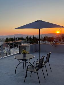 a table and two chairs and an umbrella on a roof at Acropolis Panorama Studio in Athens