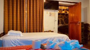 1 dormitorio con 1 cama blanca y TV en Mirador inka, en Ollantaytambo