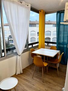 - une table et des chaises dans une chambre avec fenêtre dans l'établissement Studio Chaleureux au Cap d’Agde, au Cap d'Agde